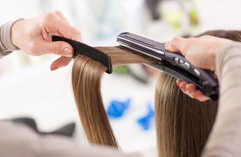 Hair straighteners being used on long brown hair